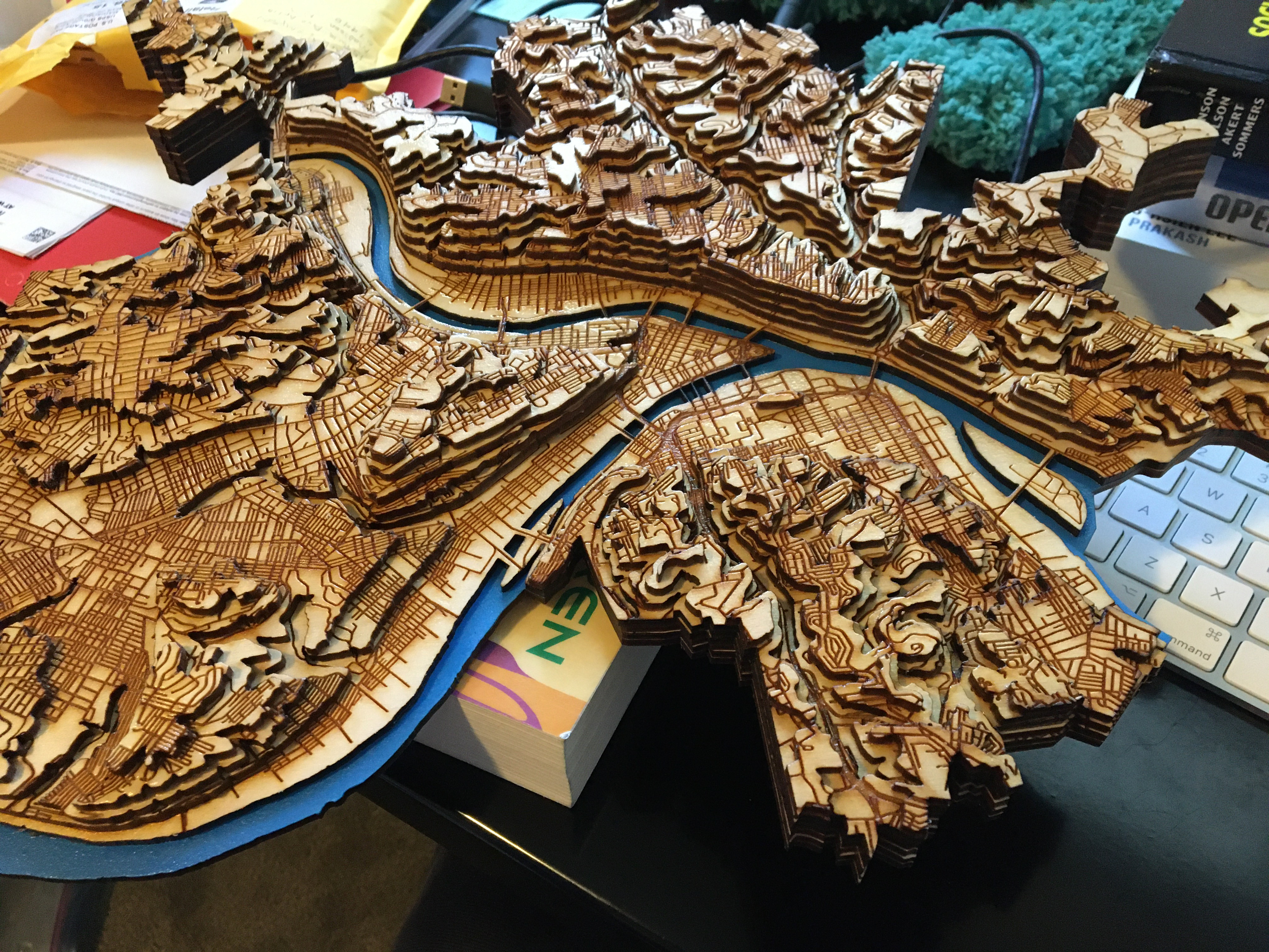 A close-up of a finished laser cut wooden topographic map of the city of Pittsburgh, facing south.